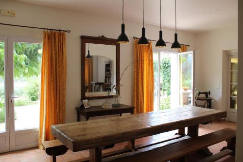 a dining room with a wooden table and orange curtains at Bastide Saint Bernard in Le Thoronet