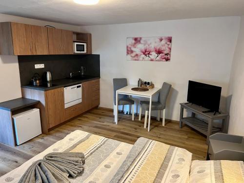 a small room with a kitchen and a table with a bed at EDER- Penzion & Apartmány in Horní Planá