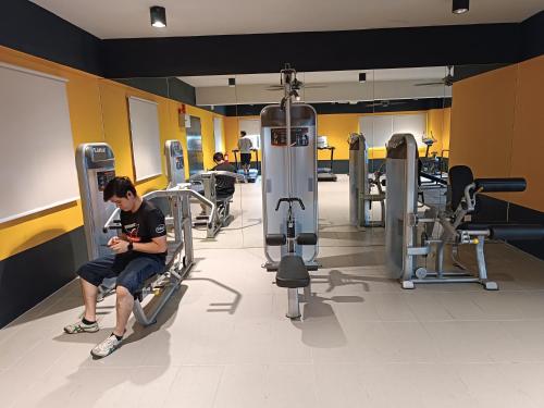 a man sitting in a gym looking at his cell phone at Aisy Homestay Putrajaya Cyberjaya KLIA in Kampung Dengkil