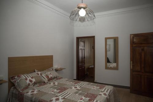 a bedroom with a bed and a chandelier at LA CASA DEL RÍO - A 13 kilómetros de Santiago in Sigüeiro