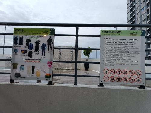 two signs on a fence next to the beach at Aisy Homestay Putrajaya Cyberjaya KLIA in Kampung Dengkil