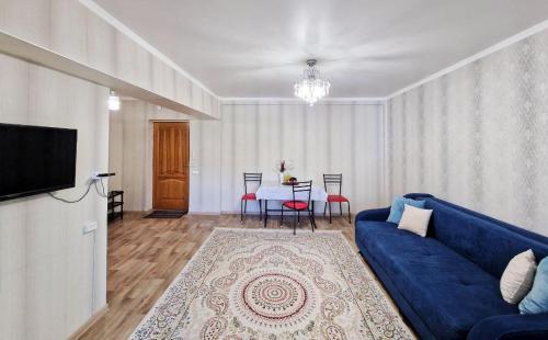 ein Wohnzimmer mit einem blauen Sofa und einem Tisch in der Unterkunft Золотой квадрат in Almaty