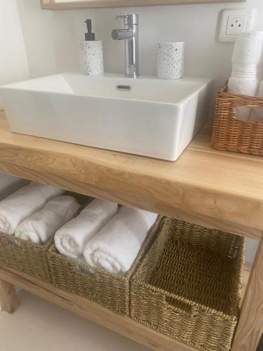 La salle de bains est pourvue d'un lavabo et de serviettes sur une étagère. dans l'établissement Maison au coeur du village, au Plan-de-la-Tour