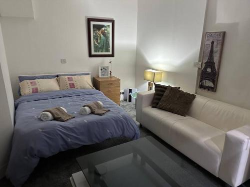 a bedroom with a bed and a white couch at Super spacious, Grnd Floor Flat in London