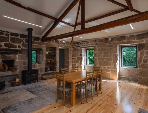 a dining room with a wooden table and a fireplace at Casa Amorim Girão in Fataunços