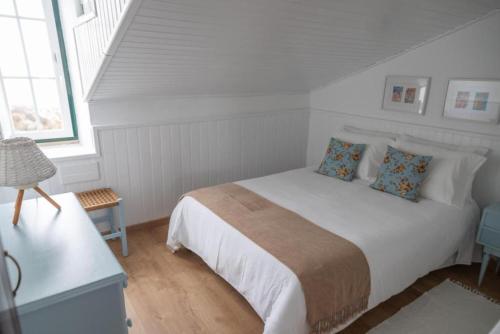 a white bedroom with a white bed with blue pillows at Casa das Marés 2 in Baleal