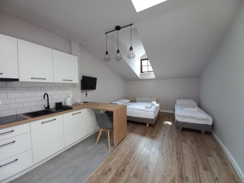 uma cozinha com armários brancos, uma secretária e uma cama em Apartamenty na Rynku Tarnów em Tarnów