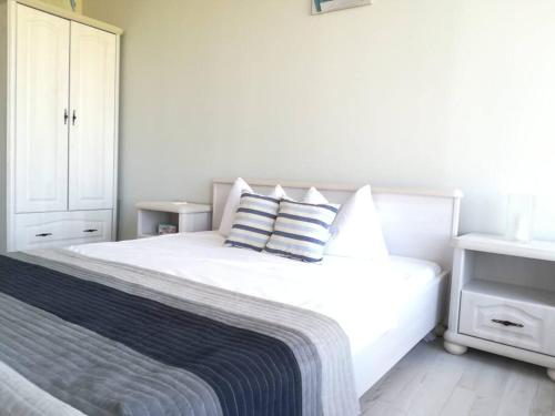 ein weißes Schlafzimmer mit einem großen weißen Bett mit Kissen in der Unterkunft Villa L3 Lighthouse Golf Resort Balchik in Baltschik