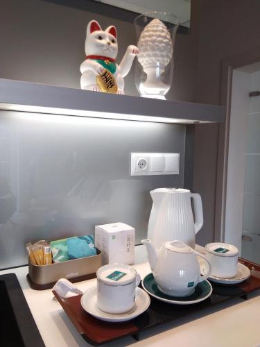 a kitchen counter with plates and cups and a tea kettle at Apartament City Center JAPAN - no smoking, free bottled water, coffea and tea in Koszalin