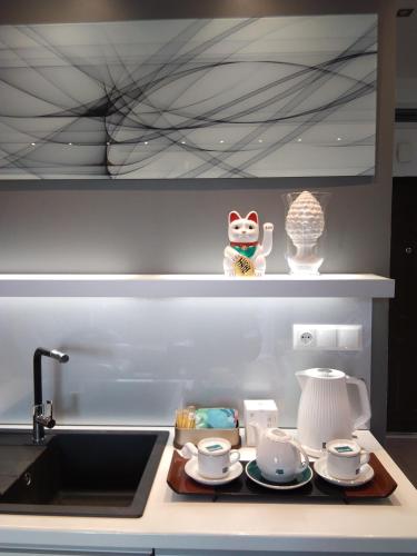 a kitchen counter with a sink with cups and saucers at Apartament City Center JAPAN - no smoking, free bottled water, coffea and tea in Koszalin