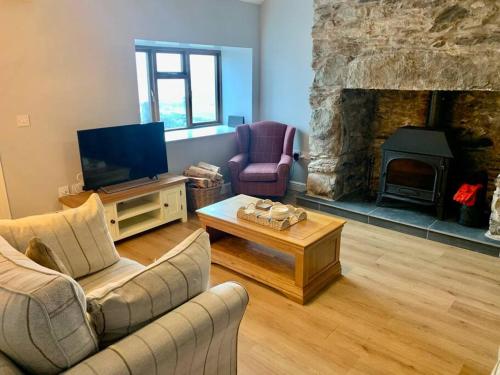 a living room with a couch and a tv and a fireplace at Welsh cottage coastal retreat with stunning views in Pen-y-groes