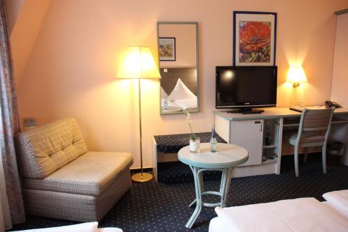 a hotel room with a couch and a tv and a table at Hotel Nordic in Norderstedt