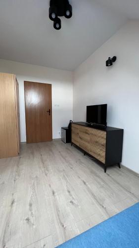 an empty room with a television and a wooden cabinet at Kraken-pokoje gościnne in Krynica Morska