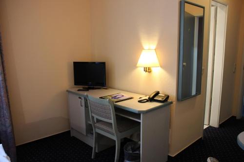 a room with a desk with a computer and a lamp at Hotel Nordic in Norderstedt