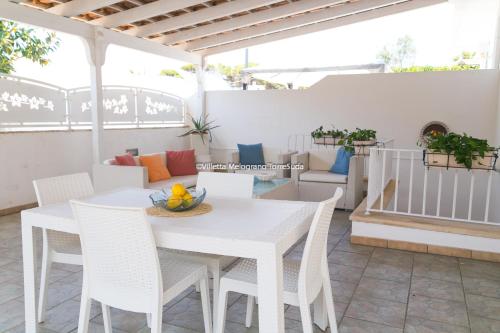 een witte tafel en stoelen op een patio bij Villetta Melograno con patio 6pax, 200m dal mare in Racale