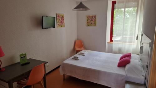 a bedroom with a bed and a desk and a television at Résidence du Rougier in Camarès