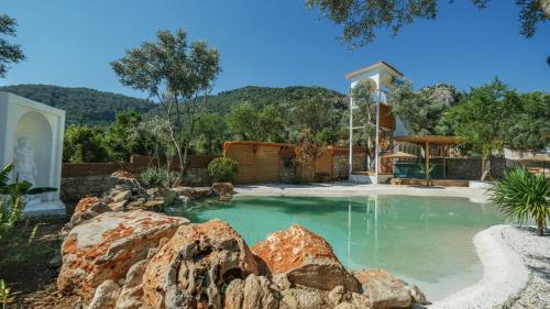 einen Pool in einem Garten mit Felsen in der Unterkunft Zai Jardin in Fethiye