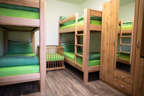 a room with three bunk beds with green sheets at Penzion Na výminku in Veselí nad Moravou