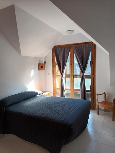 a bedroom with a bed and a large window at HOTEL FAMILIAR MAXIMINA in Sallent de Gállego