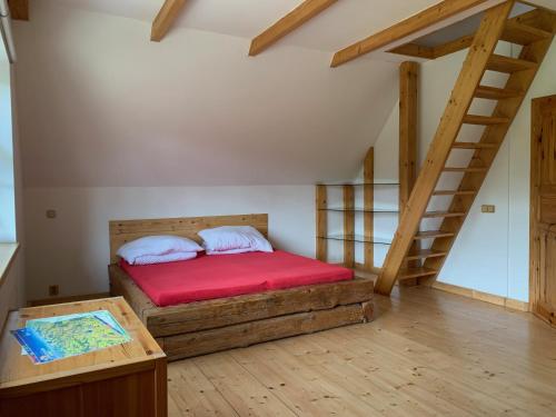 ein Schlafzimmer mit einem Bett mit einer roten Matratze und einer Treppe in der Unterkunft Slunovrat in Teplice nad Metují