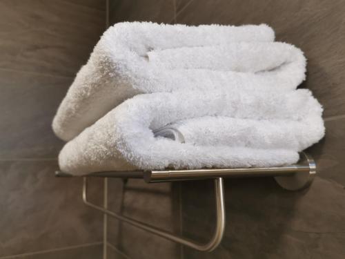 una pila de toallas blancas en un estante del baño en Apartmány Benedicta, en Benešov
