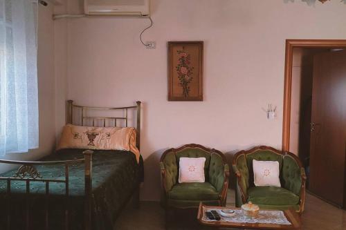 a room with two chairs and a bed and a table at Casa con impronta vintage a Nartë 