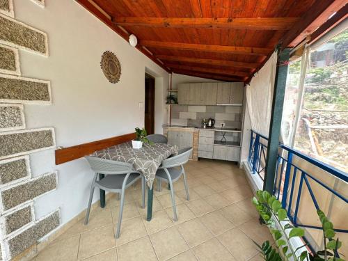 patio con mesa y sillas y cocina en Boungainvillea, en Himare