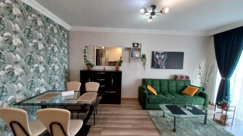 ein Wohnzimmer mit einem grünen Sofa und einem Tisch in der Unterkunft NG Cozy App in Tbilisi City