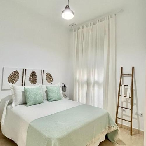 Dormitorio blanco con cama grande y escalera en Apartamento las tres lunas, en Sanlúcar de Barrameda