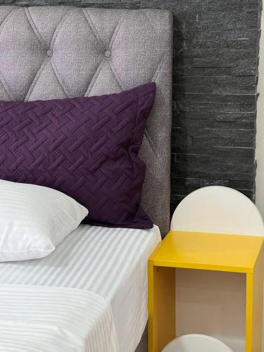 a bed with a purple pillow and a yellow table at Zani Boutique Hotel in Prizren