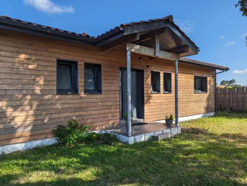une maison en bois avec un porche et une terrasse dans l'établissement Chambre privée chez l'habitant, à Parentis-en-Born