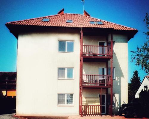 a large white building with a red roof at Kraken-pokoje gościnne in Krynica Morska