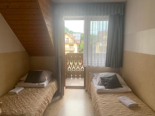 two beds in a room with a window at Nad Brzózkami in Szczawnica
