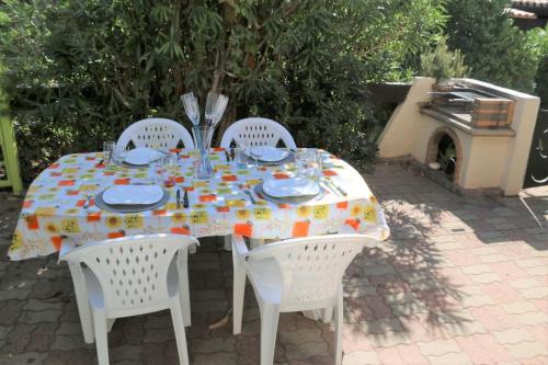 une table avec trois chaises blanches et une nappe dans l'établissement Villa 19, Port Vénus au village naturiste, au Cap d'Agde