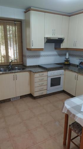 - une cuisine avec des placards blancs, un évier et une table dans l'établissement Casa Celita, à Poio