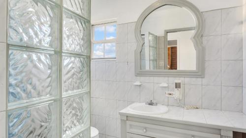 a white bathroom with a sink and a mirror at Edwards Guesthouse in Sandy Ground Village