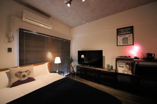 a bedroom with a bed and a flat screen tv at goom Hotel Nakasu in Fukuoka