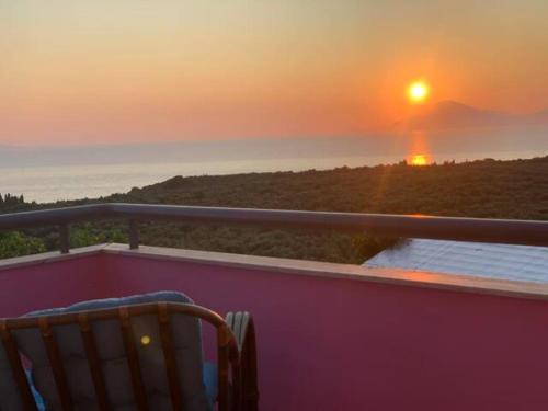 a chair sitting on a balcony watching the sunset at Anastasias Villa in Kastro Kyllini