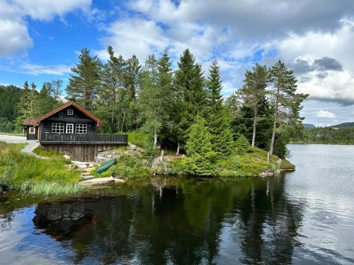 una cabaña a orillas de un lago con árboles en Holiday cottage with sauna close to Kjerag en Tjørhom
