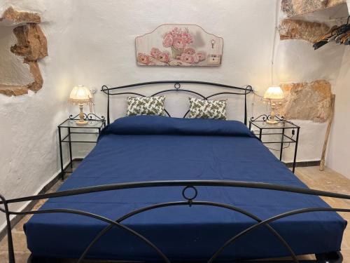 a bedroom with a blue bed with two lamps at Trulli delle succulente in Capilungo