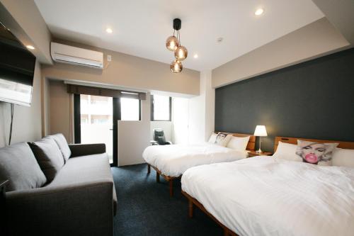 福岡市にあるZONK HOTEL Nakasuのベッド2台とソファが備わるホテルルームです。