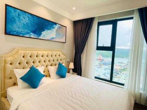 Un dormitorio con una cama con almohadas azules y una gran ventana. en Căn hộ Altara 5 sao Quy Nhơn - Thiên Trang apartment, en Quy Nhon