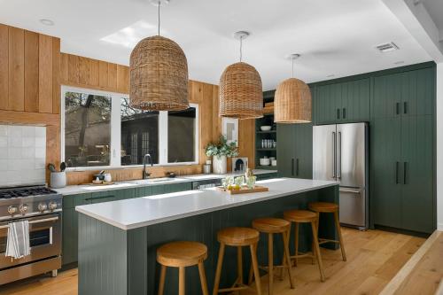a kitchen with green cabinets and a counter with stools at Mojito Haus with Hot tub in Fredericksburg
