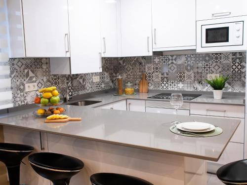 a kitchen with white cabinets and a counter with fruit on it at APARTAMENTO GAEL- PLAZA ESPAÑA in Avilés