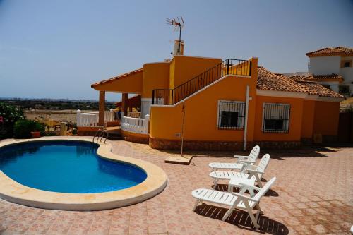 un patio con sillas, una piscina y una casa en Villa Canamon en Mutxamel