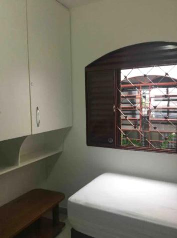 Habitación blanca con ventana, cama y mesa en Se hospede na casa da Márcia, en Jundiaí
