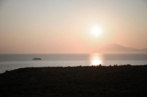 a sunset over the ocean with a boat in the water at Anastasias Villa in Kastro Kyllini