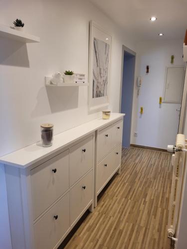 a kitchen with white cabinets and a wooden floor at Les Jacynthes in Colmar