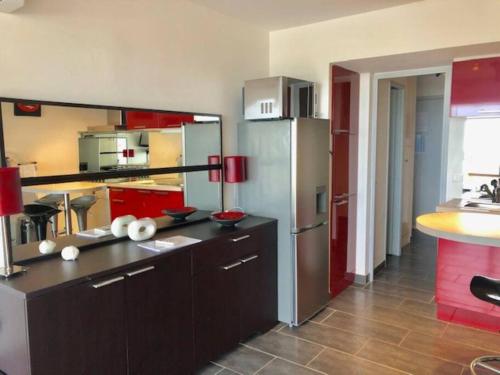 une cuisine avec des armoires rouges et un réfrigérateur dans l'établissement Studio 567, Port Nature 5 au village naturiste, au Cap d'Agde