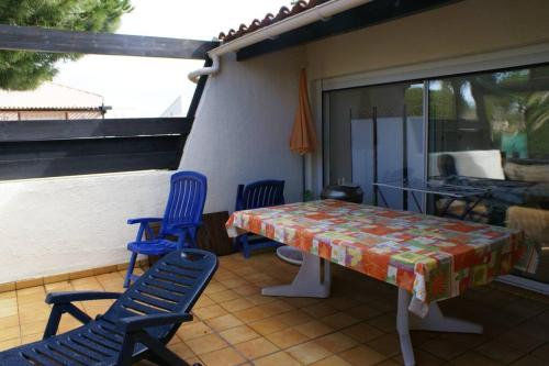 une table et des chaises assises sur une terrasse couverte avec une table et des chaises dans l'établissement Appartement Duplex 301 Tennis Village 6 Personnes, au Cap d'Agde